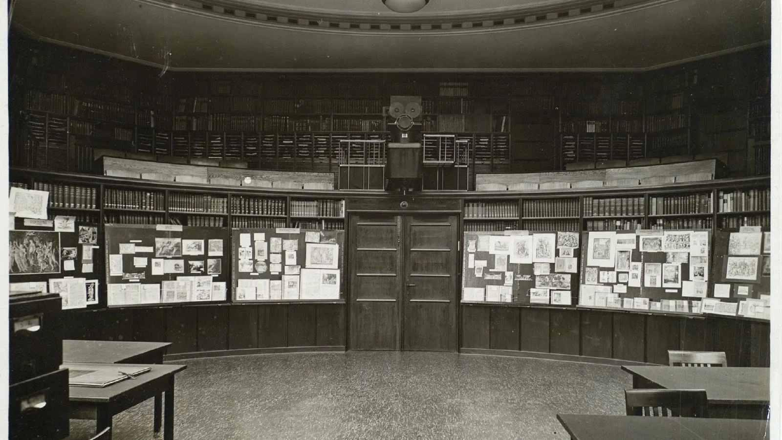 Czytelnia biblioteki Warburga: reprodukcje obrazów zestawione na tablicach pod regałami z książkami